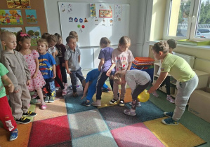 Dzieci podają sobie piłkę pod nogami.