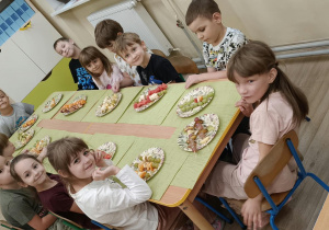 Dzieci siedzą przy stole.