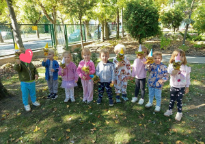 Dzieci pozują do zdjęcia z pacynkami z liści.