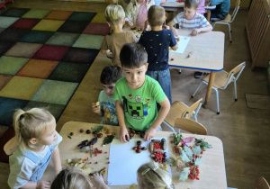 Dzieci przy stolikach układają obrazy z darów jesieni