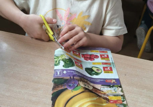 Dziewczynka wycina warzywa z gazety.