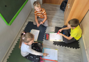 Dzieci kończą kolorowanie twarzy przedstawionych na obrazku.