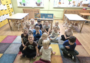 Dzieci pozują do zdjęcia w klasie przedszkolnej przy kalendarzu pogody