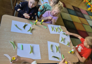 Dzieci przy stolikach wykonują pracę plastyczną